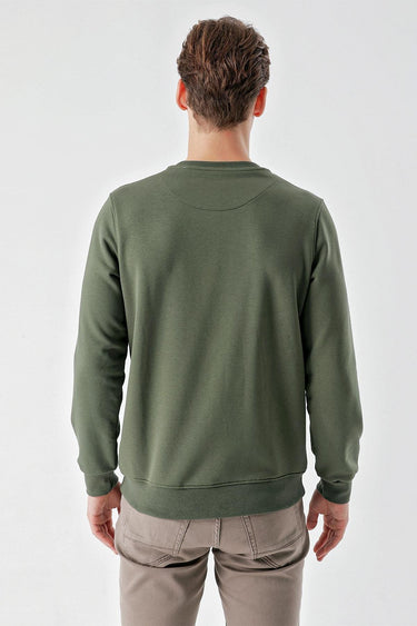 Man wearing green crew neck sweatshirt and beige pants, shown from the back
