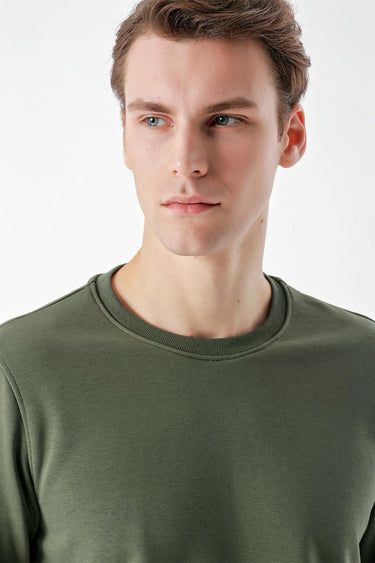 Man wearing a green crew neck basic t-shirt, close-up on upper body and shirt texture