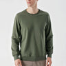 Man wearing a green crew neck long sleeve sweatshirt with beige trousers